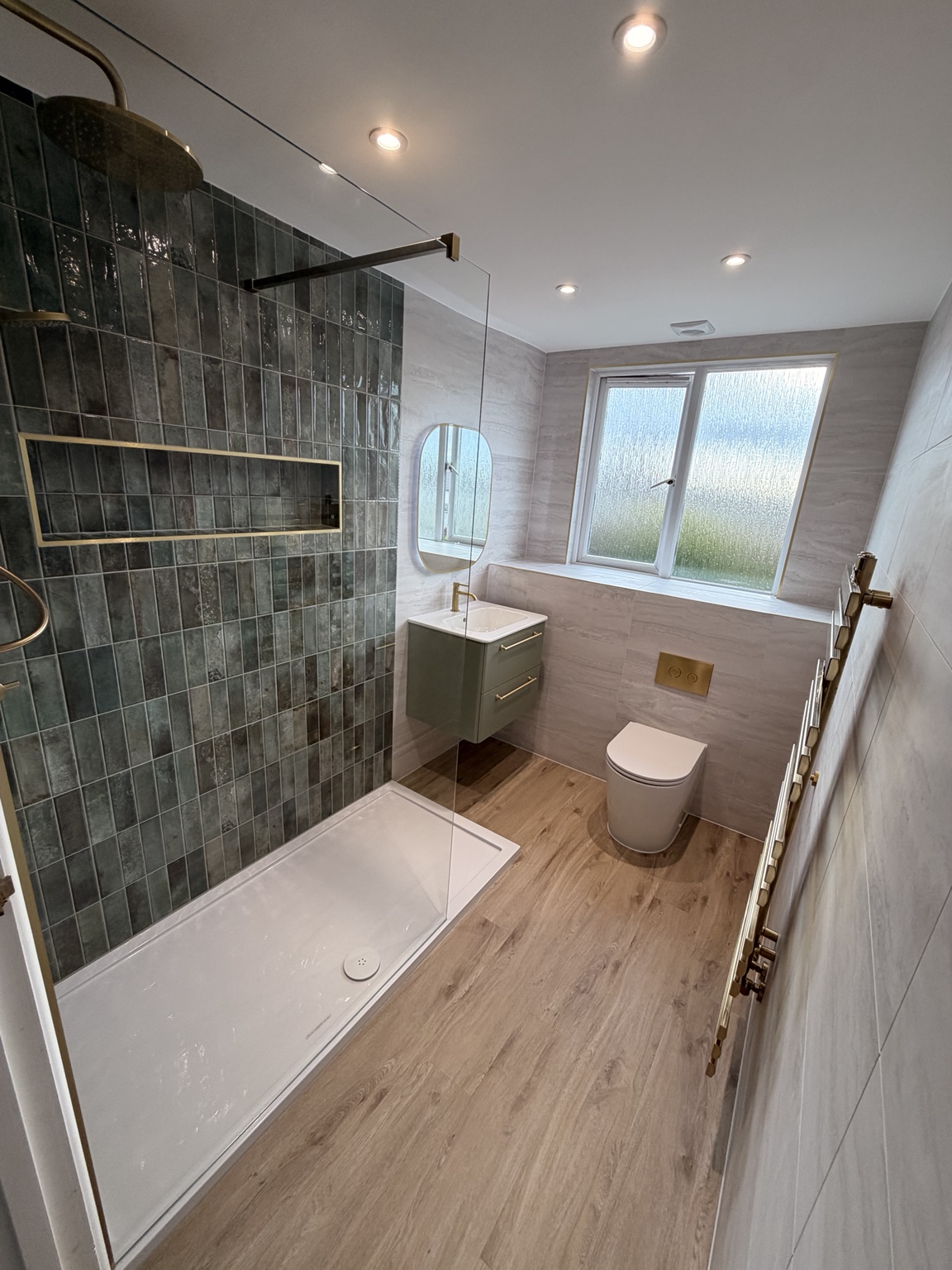 Walk-in shower with green feature tiles and brushed brass details