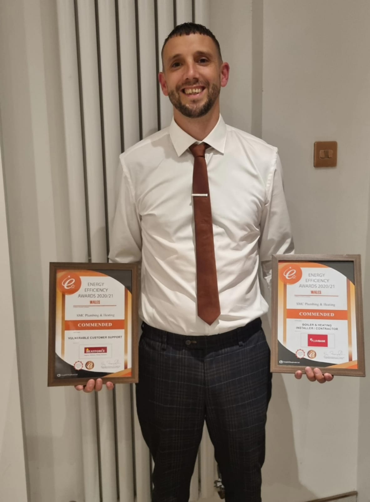 Scott McClure holding SMC Plumbing and Heating's two Energy Efficiency Awards Wales commendations