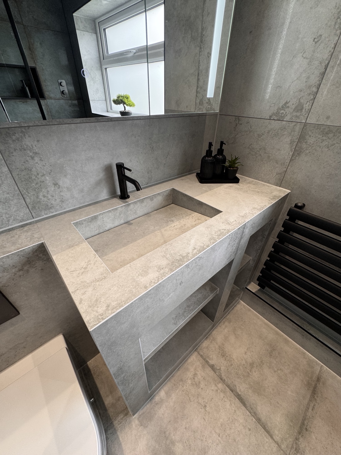 Mitred edges of the custom tiled basin with inset bowl and black tap