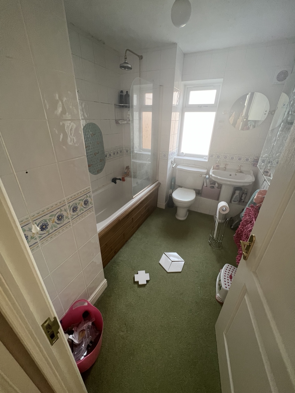 Bathroom before refurbishment with an older bath, pedestal basin and green floor